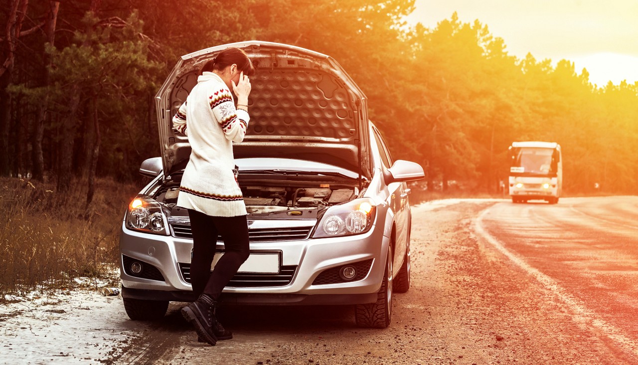 A woman alone on a rural road with her car hood up and she's on her phone calling for help.