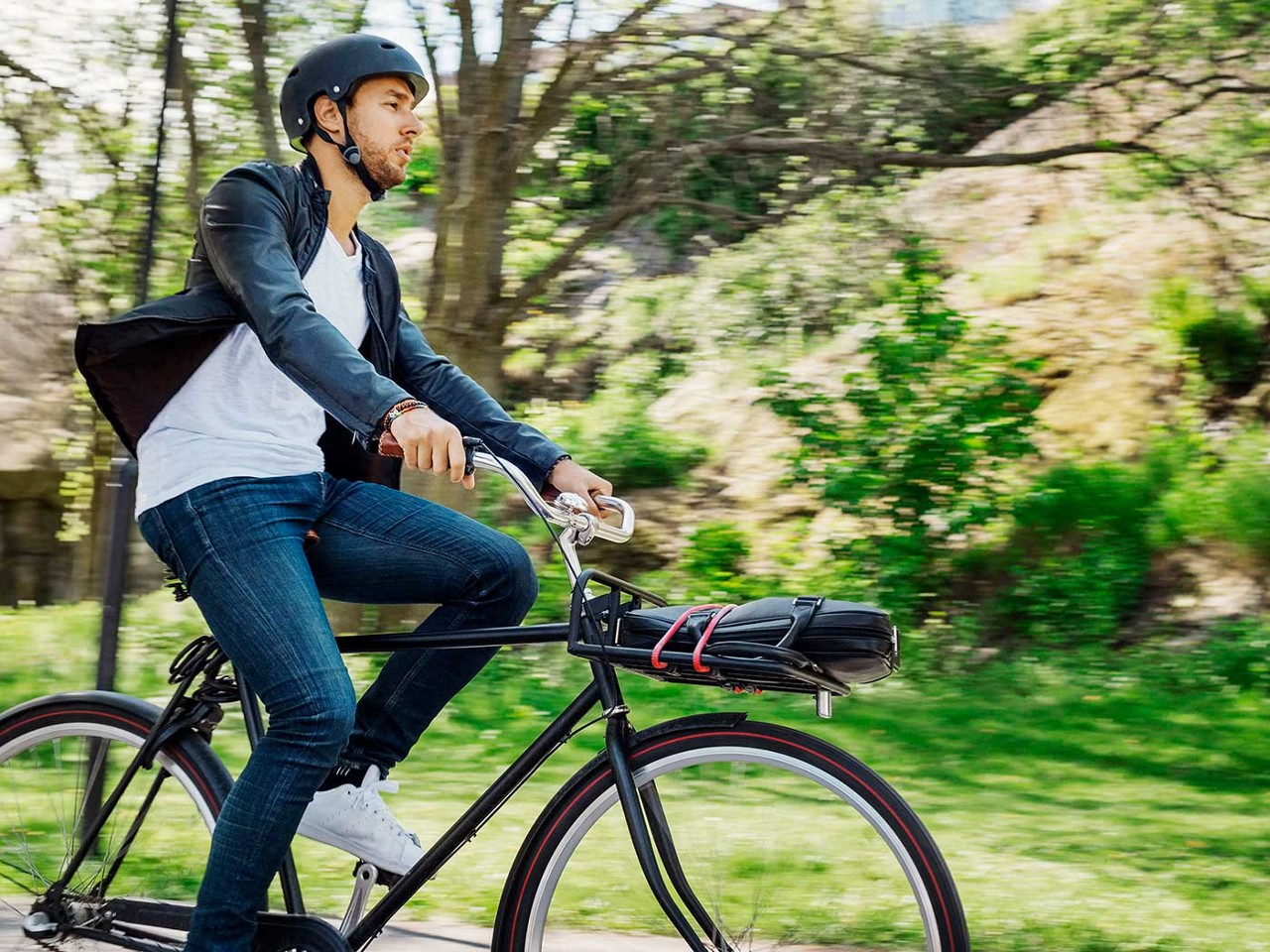 A young man riding a bike through a park.