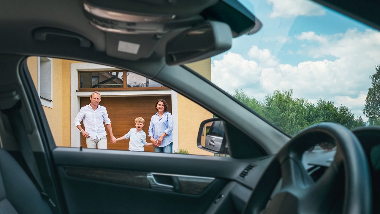 A family of three walking from their garage toward their car.