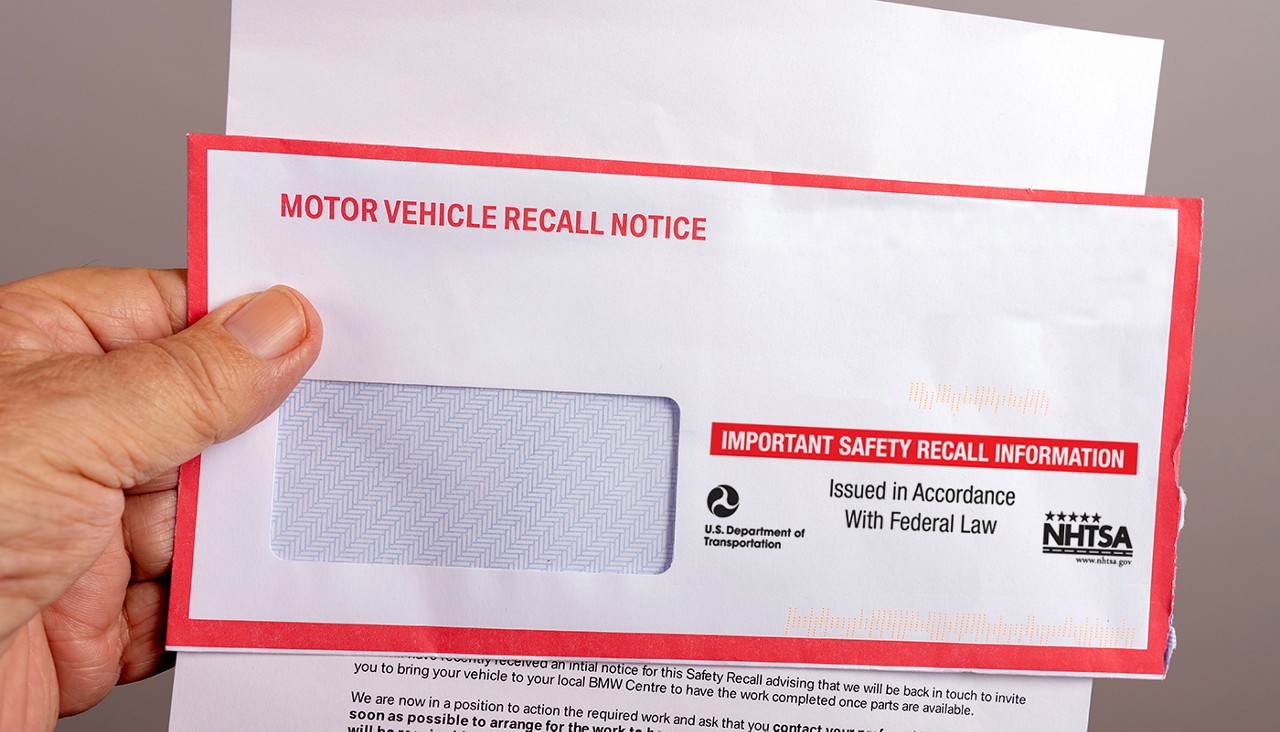A person holding a vehicle recall notice that came in the mail.