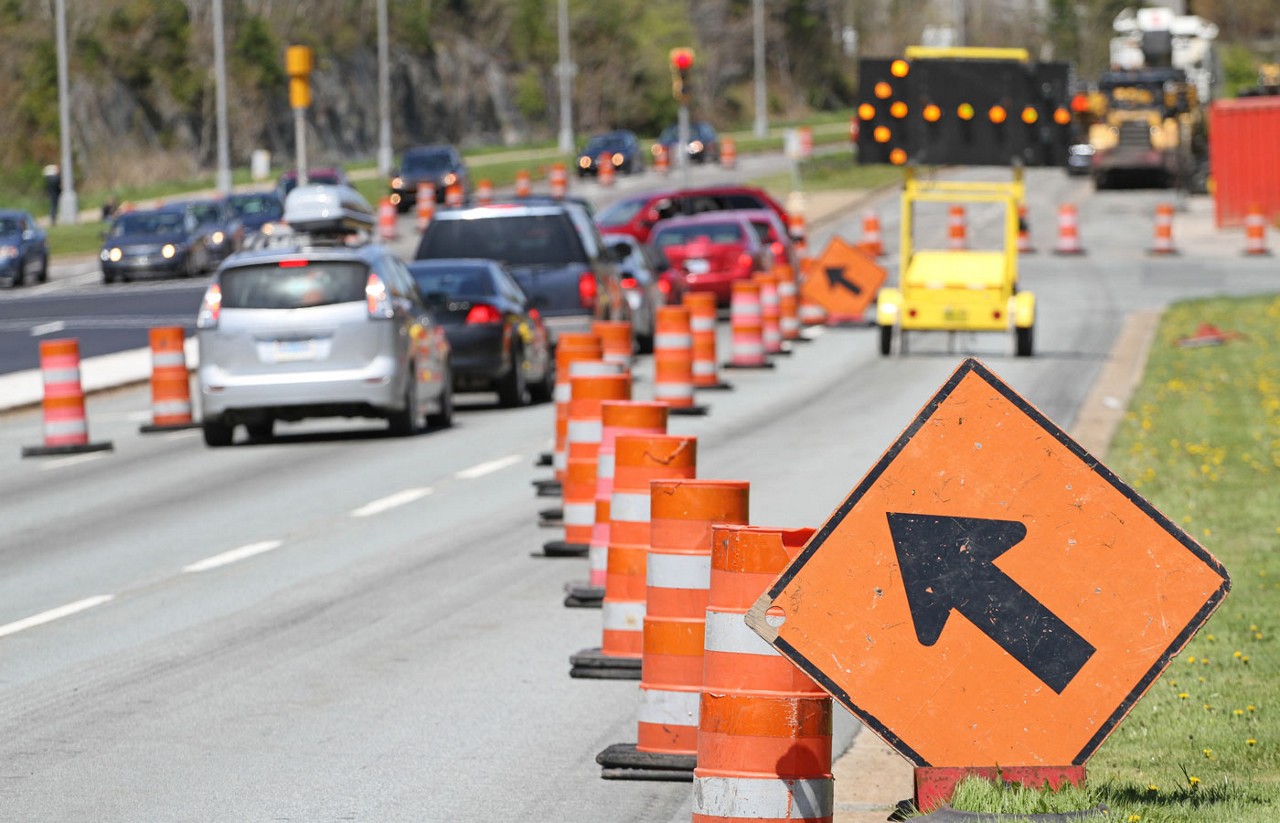 An example of a zipper merger on a road with various signs pointing the direction for cars to move to in order to merge.