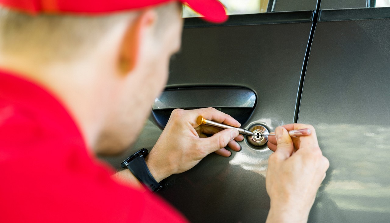 locksmith opening car door with lockpicker