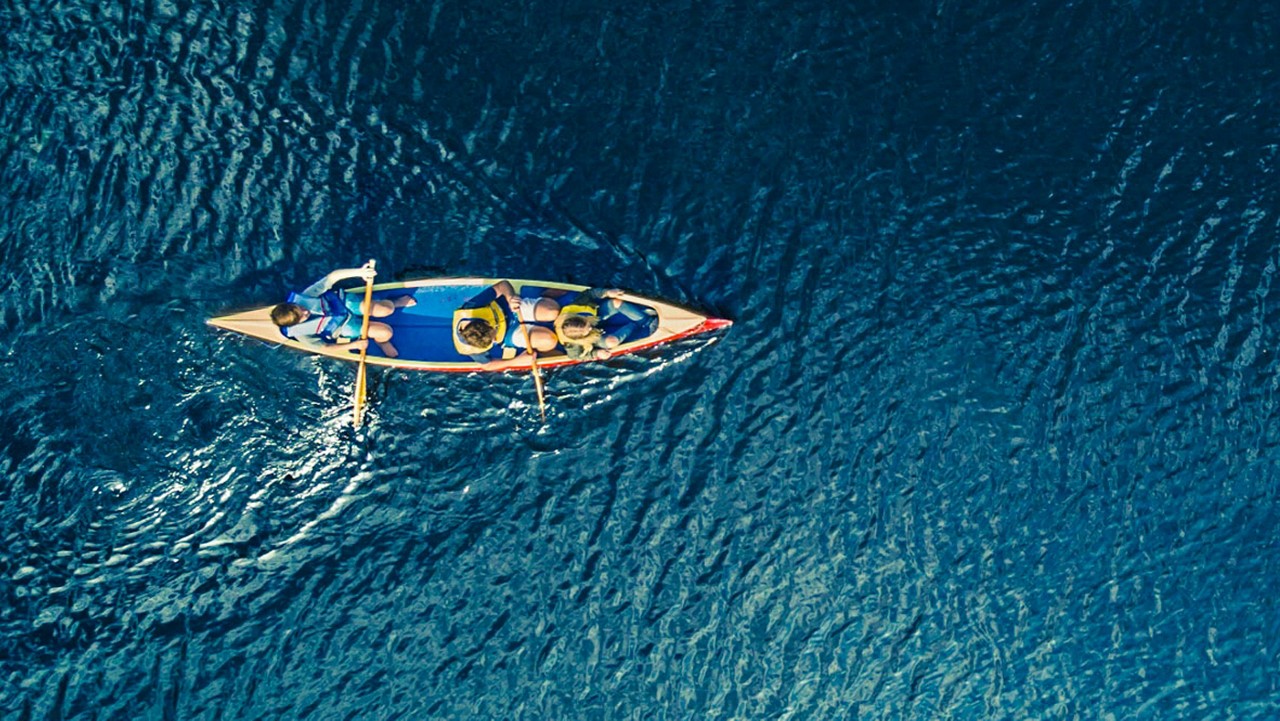 An aerial view of a canoe with three people in the boat.