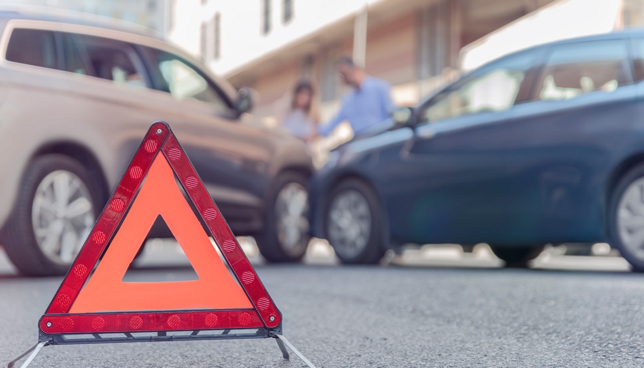 A safety reflector alerting others to a car crash in the foreground with two cars in the background that were in a crash.