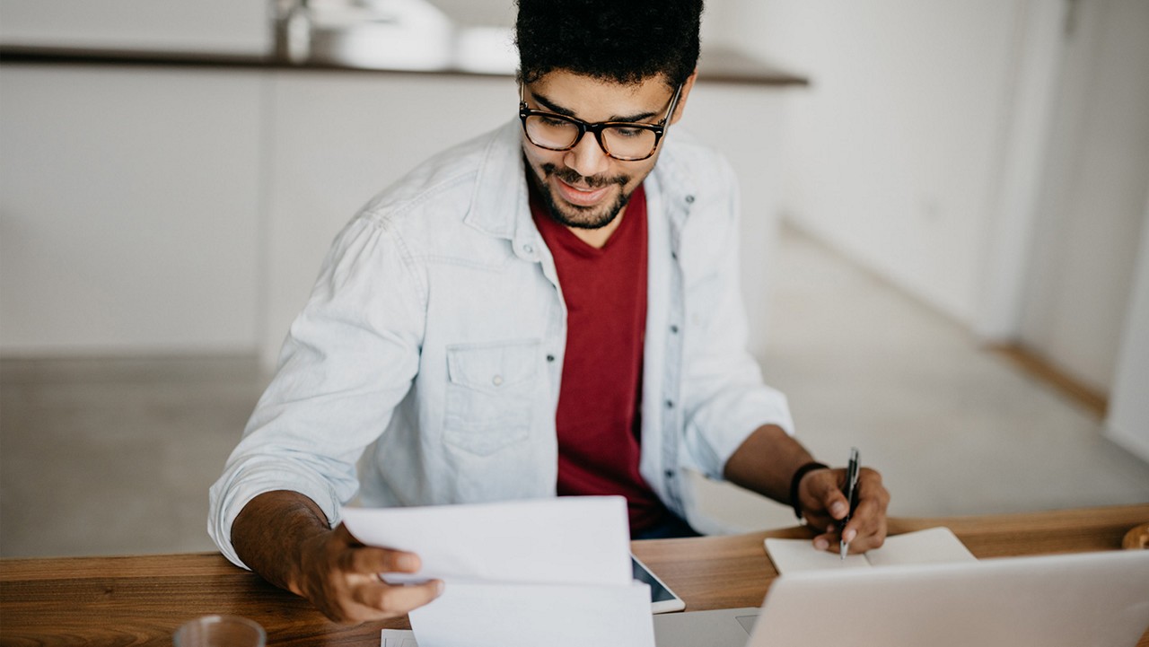 A young man reviewing paperwork at a desk.