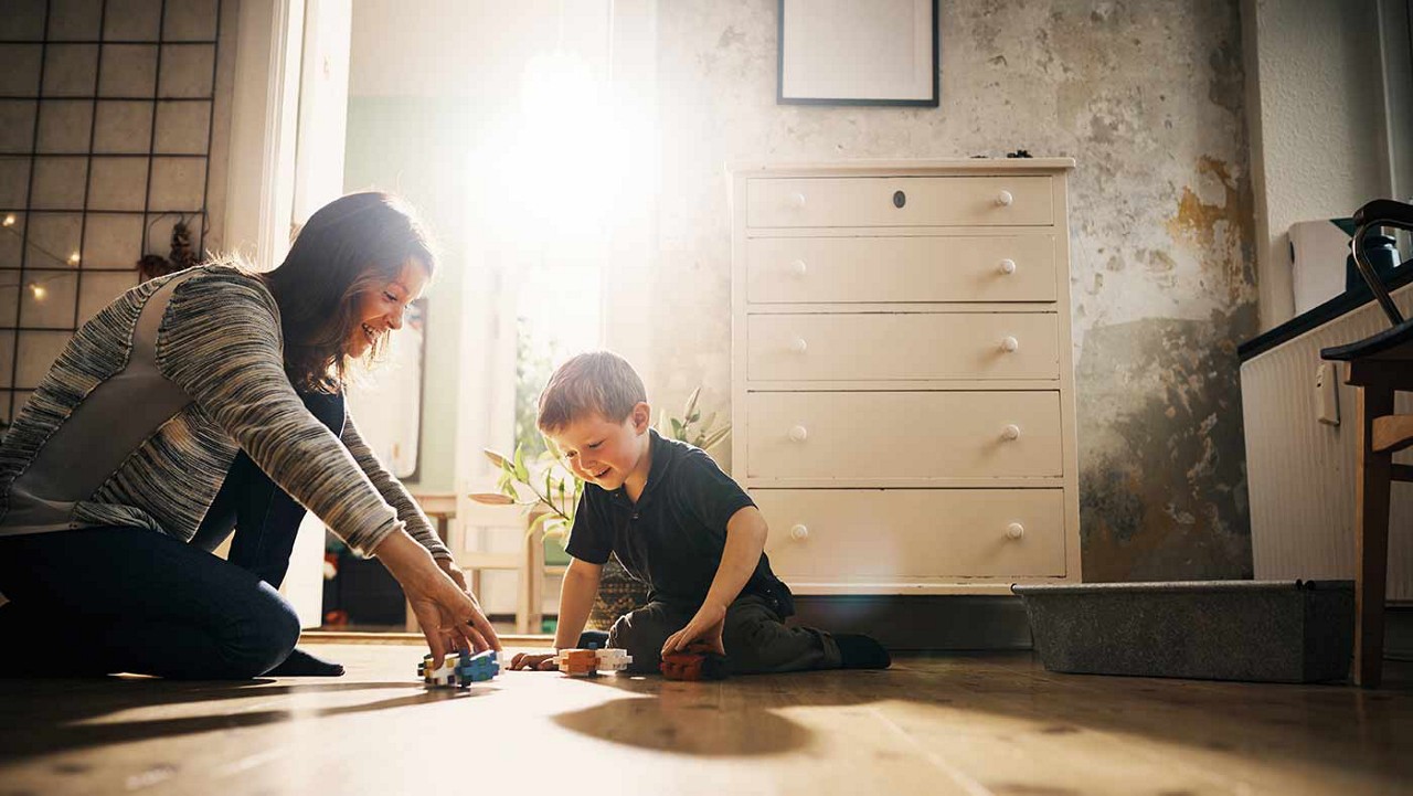 A mother playing on the floor with her son.