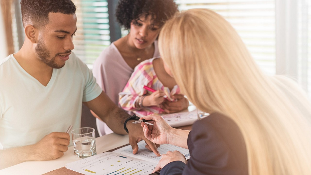 A young couple with a child signing papers with an insurance agent.