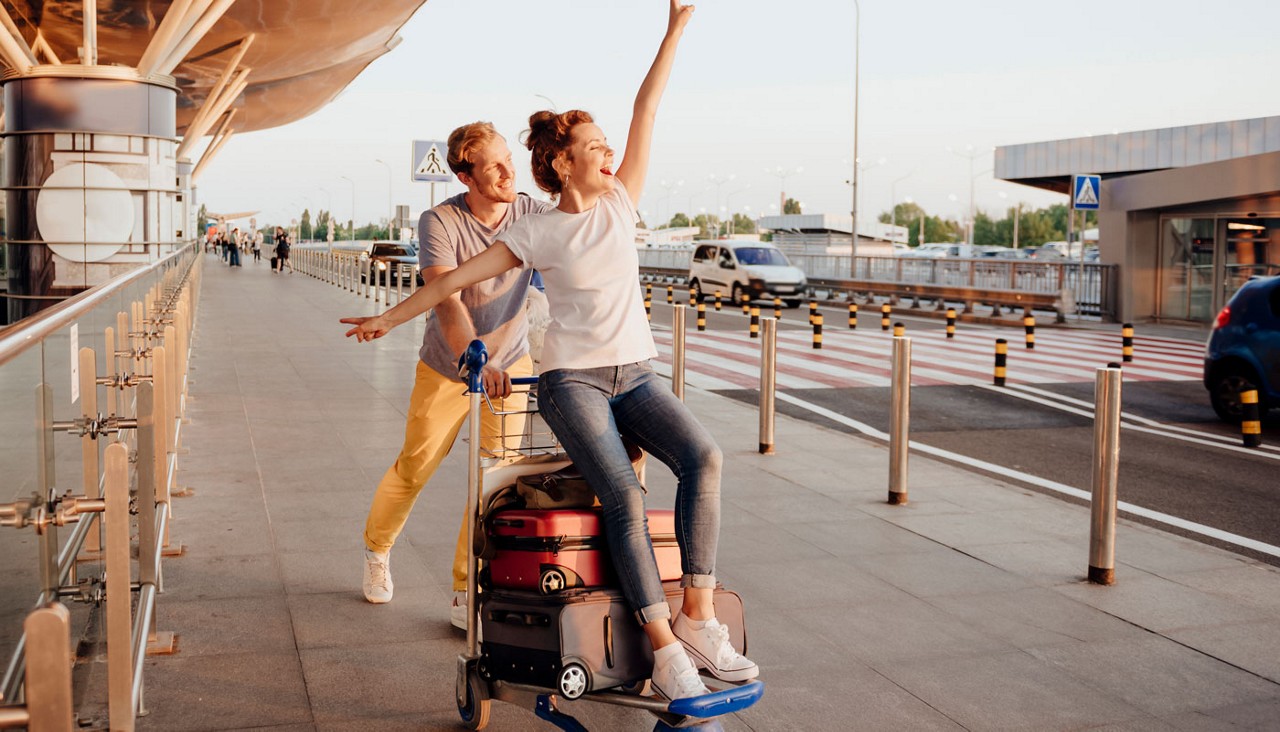Loving couple having fun at the airport with luggage carrier  before going on trip 