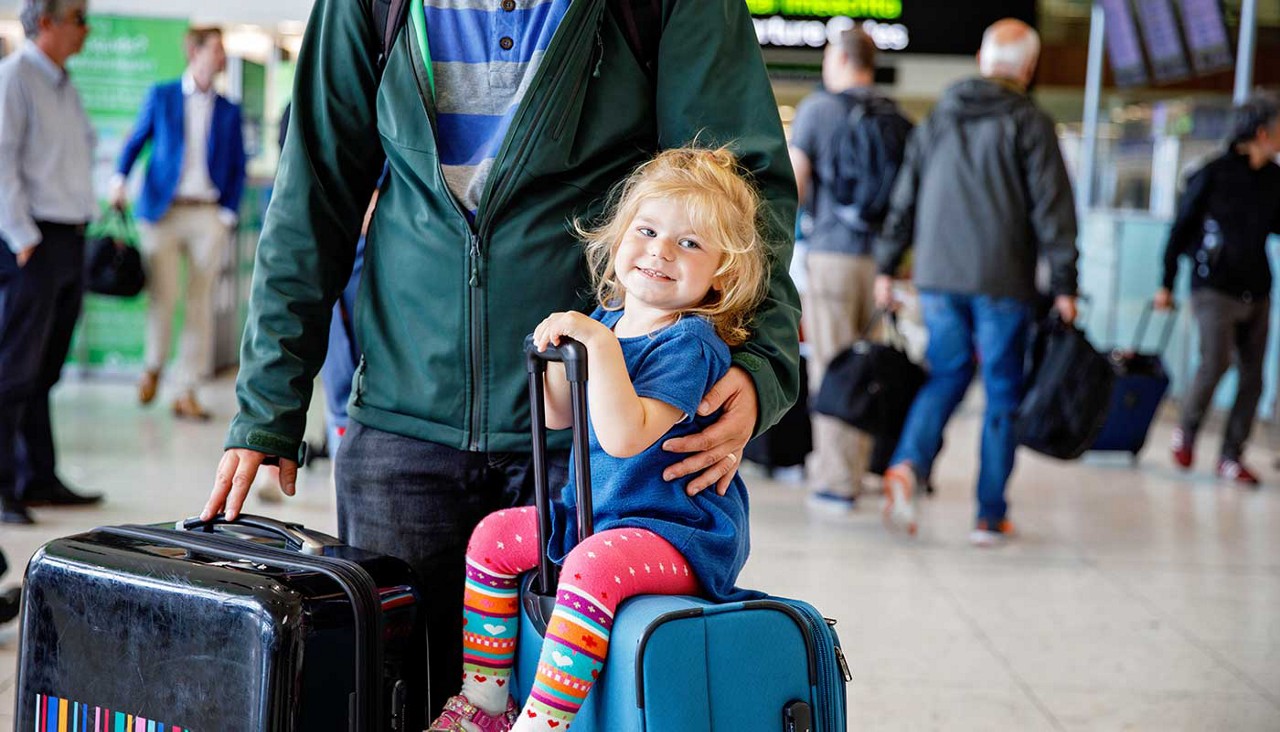 Toddler sitting on a suitcase at the airport