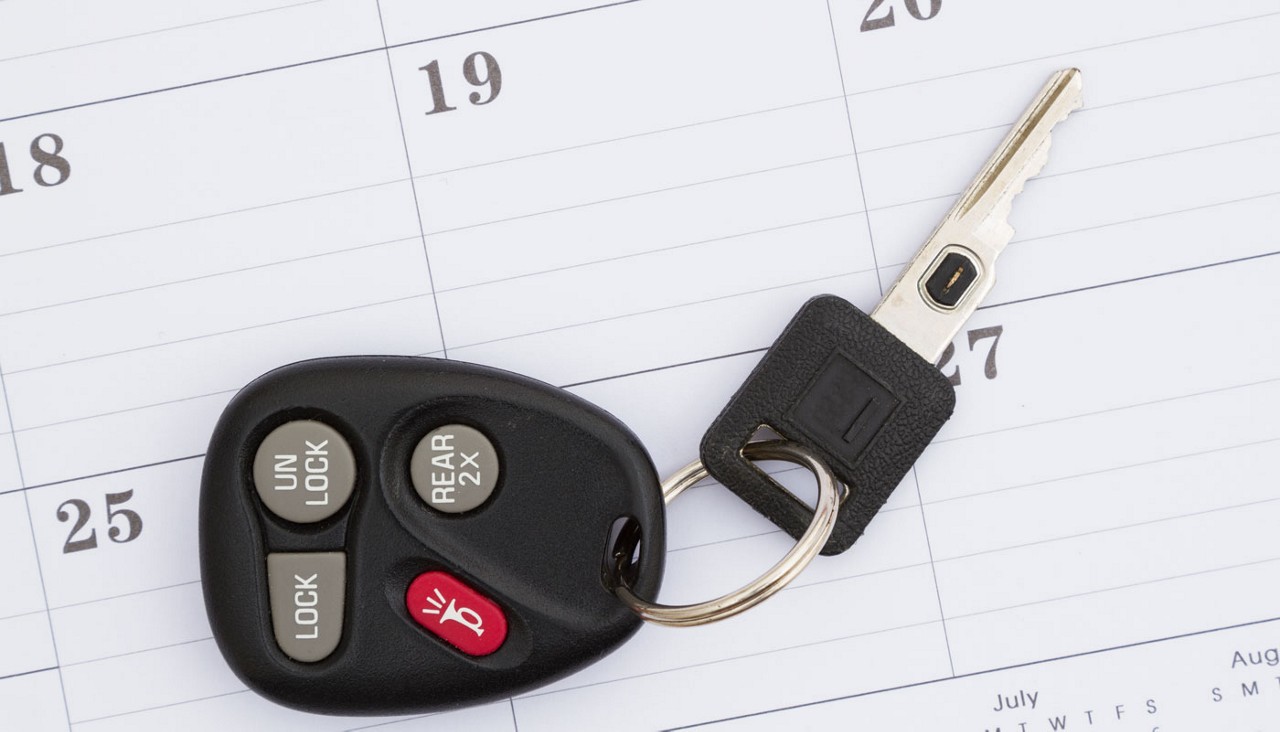 A picture of a car key laying on top of a calendar.