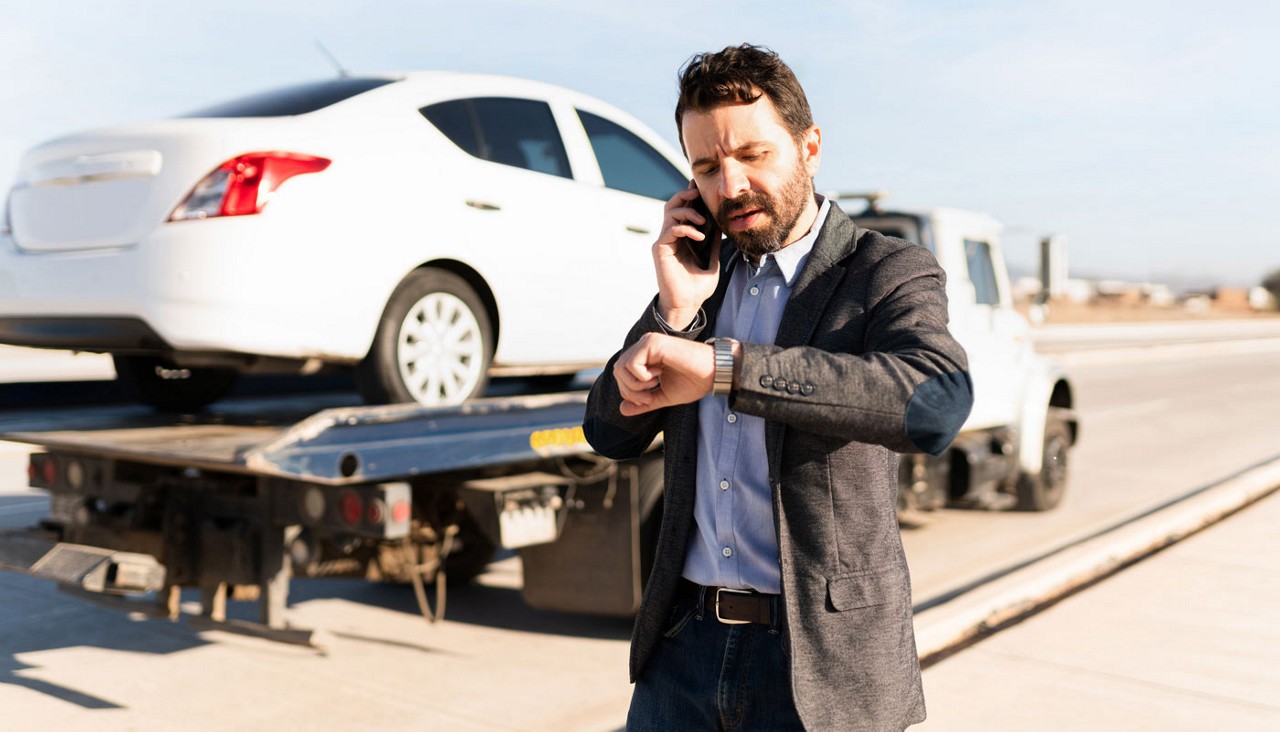 Man talking and looking at his watch next to a tow truck