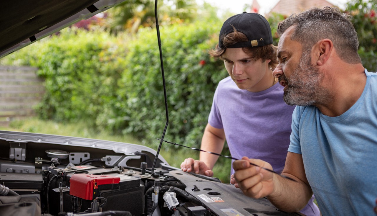 father and son checking the oil in their vehicle at home