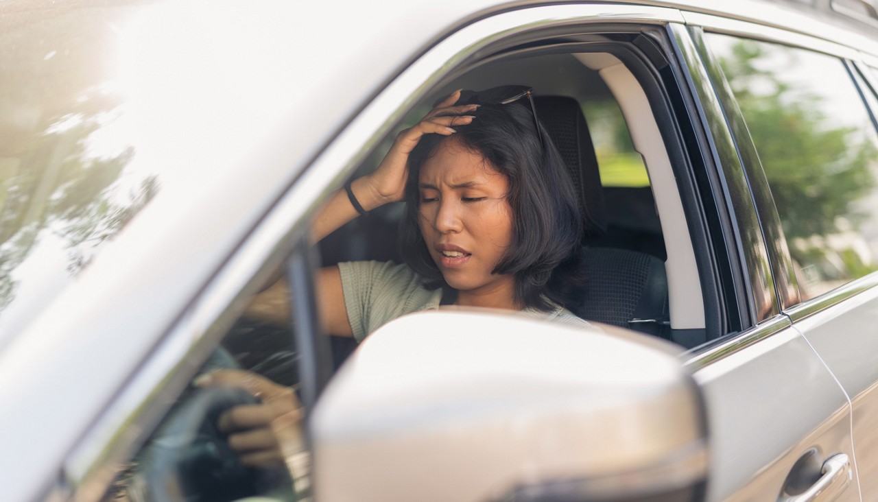 Woman in car with hand on her head in frustration