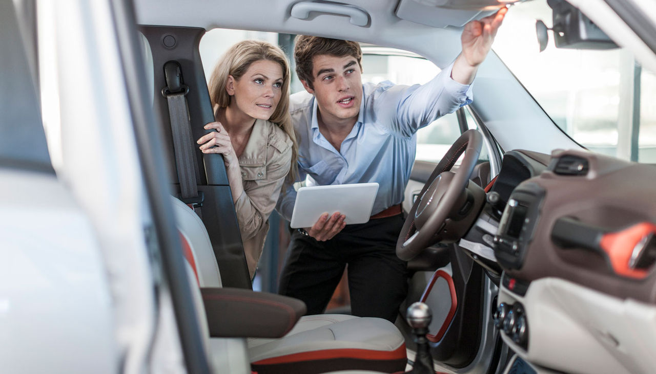 Car dealer showing new car to woman