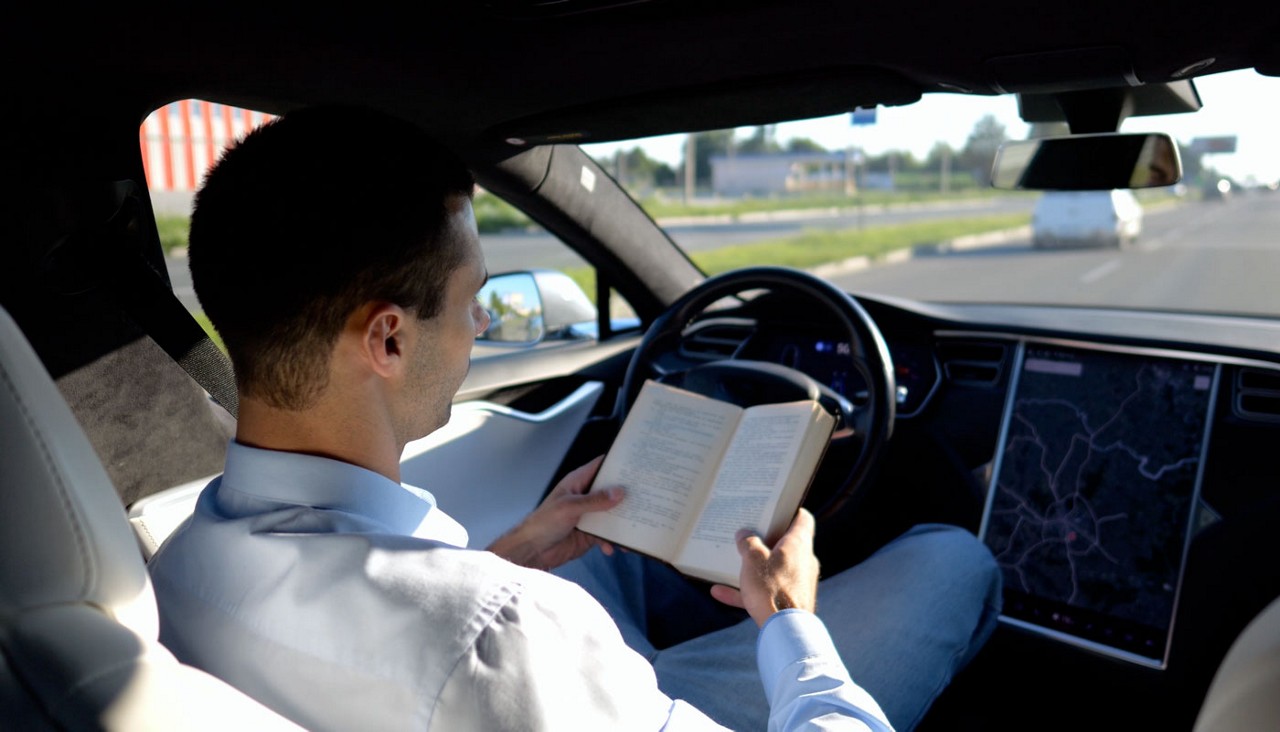 Businessman hand holding book while riding in autonomous vehicle