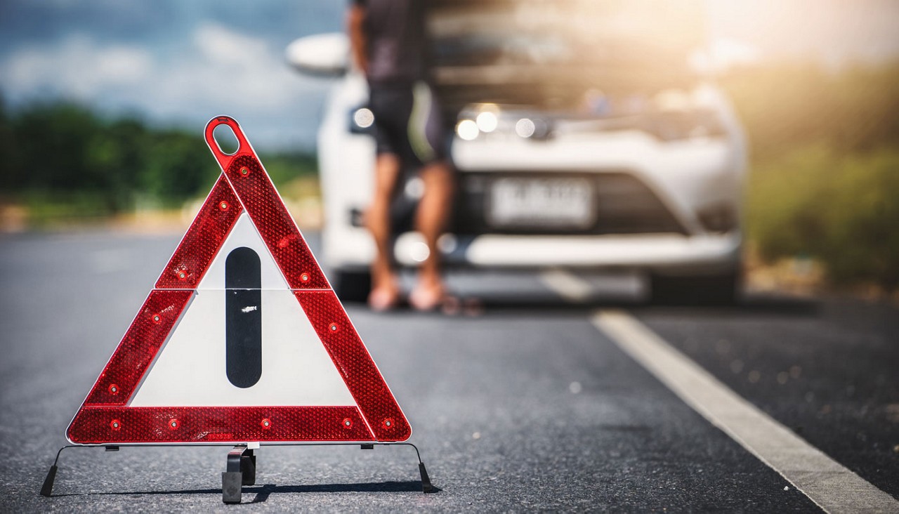 Emergency stop sign and man with broken down car on the road