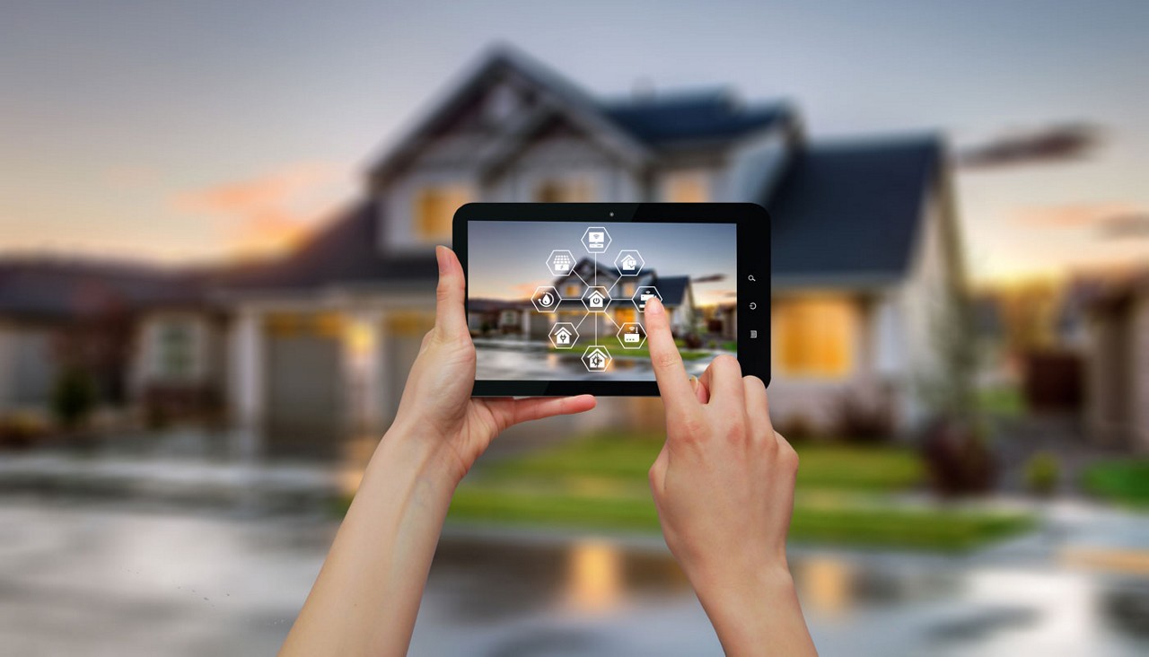 Hands holding smart phone showing outside of house with icons for smart home control