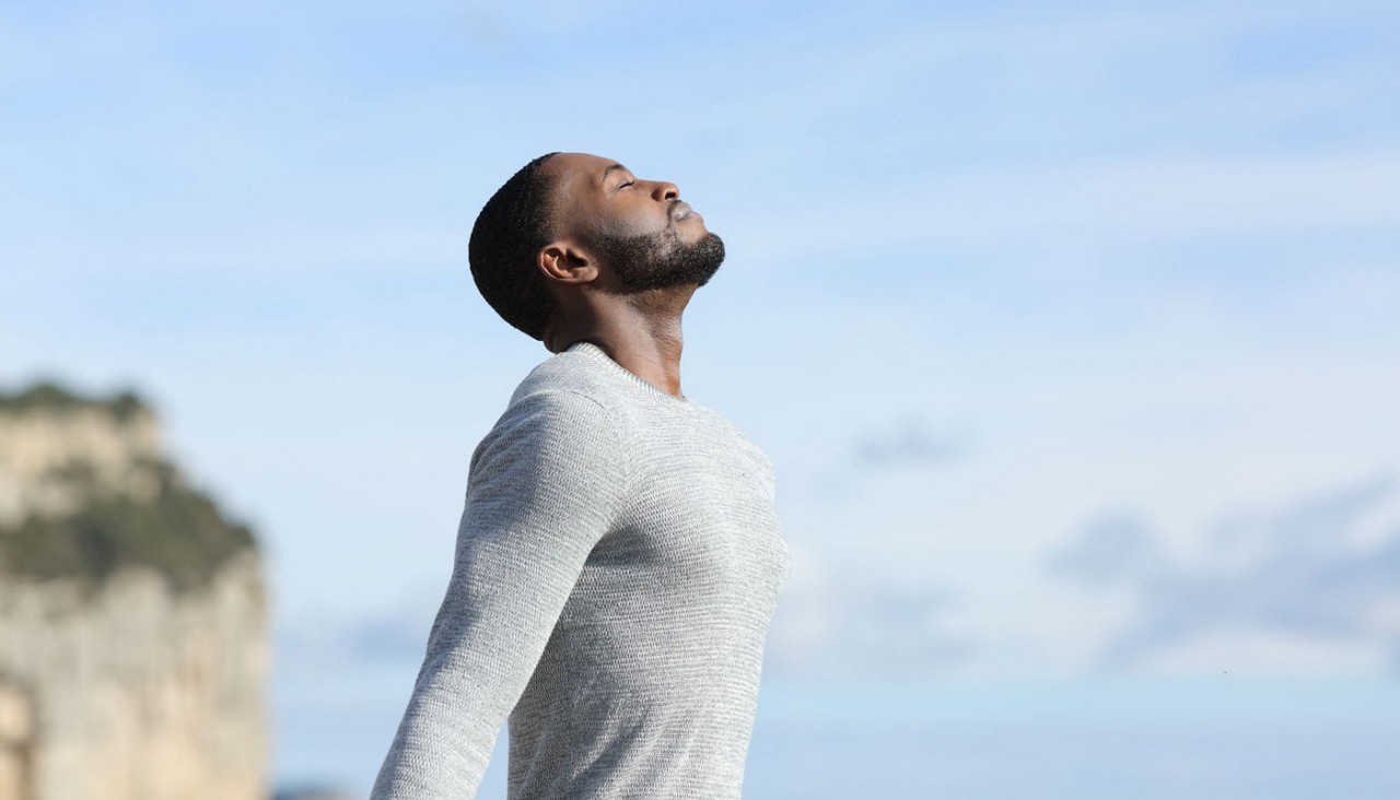 A man on a beach breathing in the salt air