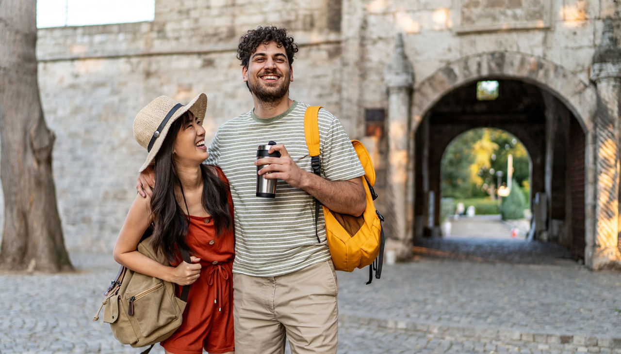 Young tourist couple with backpacks walking through an historic site in Europe.