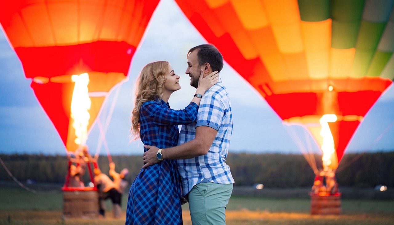 A couple embracing in front of two hot air balloons