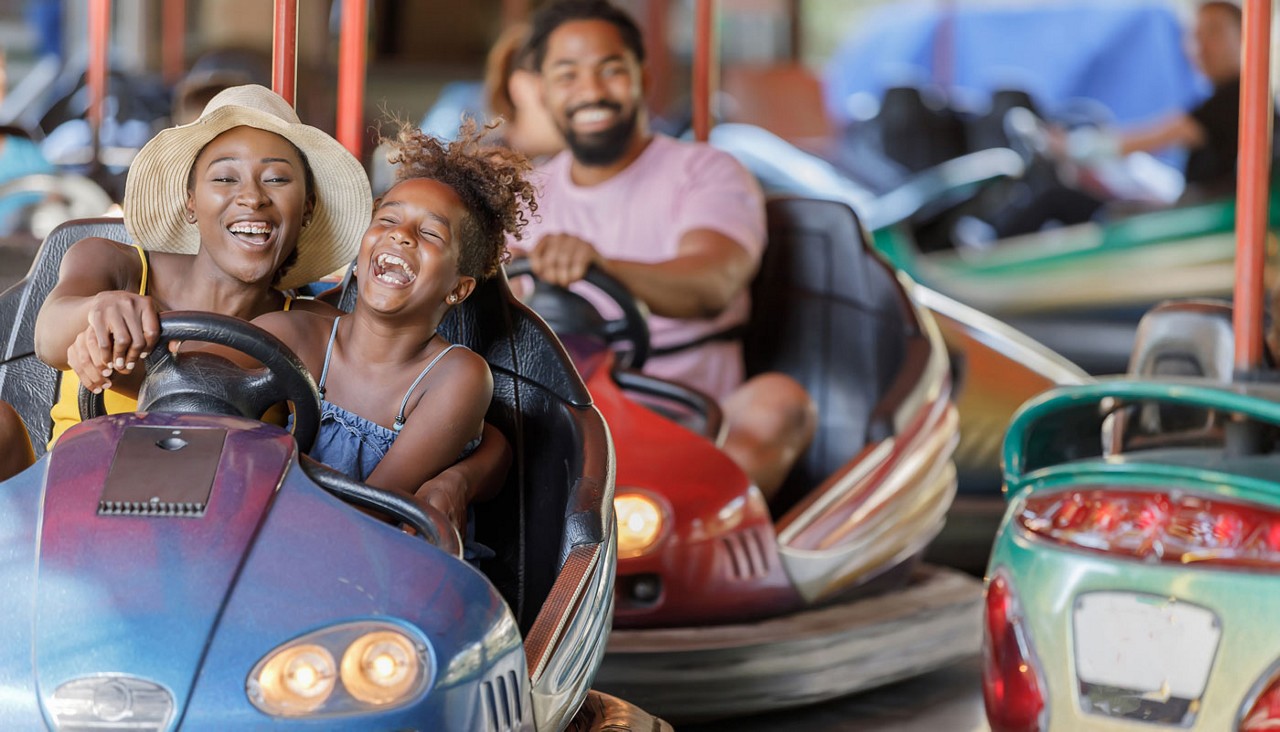 A family of three in bumper cars in an amusement park. 